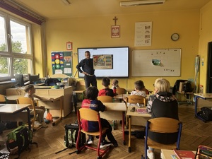 policjant prezentuje uczniom tablicę edukacyjną z sytuacją drogową (1)