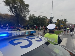 policjant ruchu drogowego czuwa nad bezpieczeństwem biegaczy