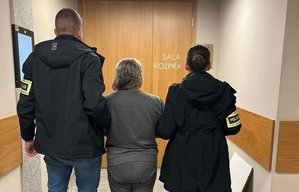 Policjant i policjantka operacyjni prowadzą zatrzymaną kobietę na salę rozpraw