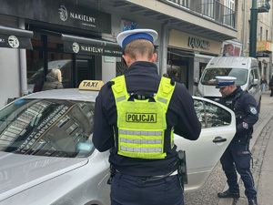 policjanci dokonują kontroli taksówki