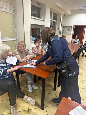 02 Policjantka rozdaje broszury informacyjne seniorom