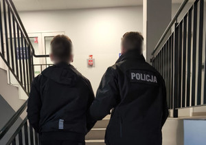 policjant prowadzi zatrzymanego po schodach