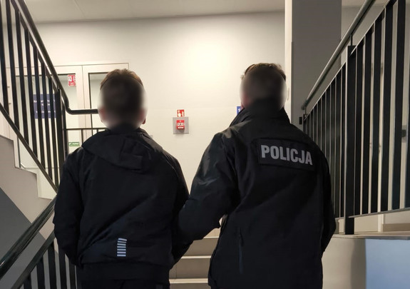 policjant prowadzi zatrzymanego po schodach