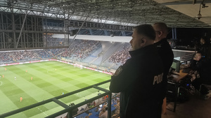 dowodzący działaniami policjanci obserwują zachowanie kibiców podczas meczu