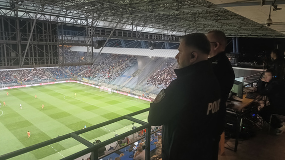 dowodzący działaniami policjanci obserwują zachowanie kibiców podczas meczu