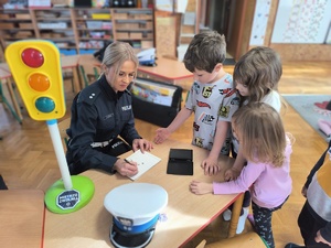 pilicjanta i dzieci rozwiązują zadania