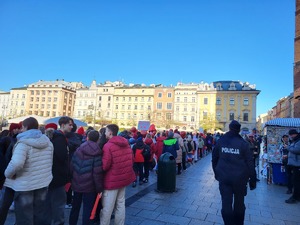 uczniowie biorący udział w przemarszu w asyście policjanta wkraczają na płytę rynku