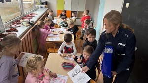 funkcjonariuszka wręcza dzieciom malowankę