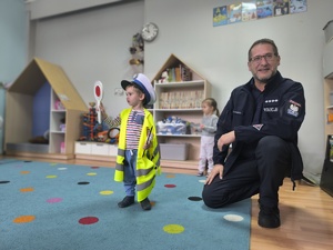 policjant obok dziecka ubranego w kamizelkę