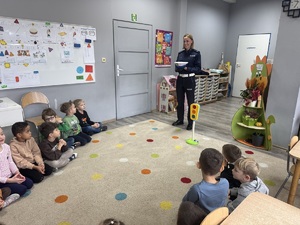 policjantka pokazuje czapkę policyjną, dzieci siedzą na dywanie