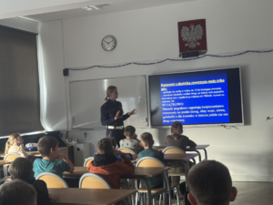 dzieci w ławkach, policjantka pokazuje slajd2