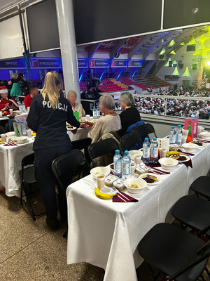 policjantka rozdająca ulotki senirom siedzącym przy stołach