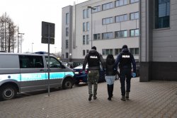 policjanci prowadzą zatrzymaną kobietę