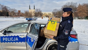 policjantka z paczką ubrań przy radiowozie