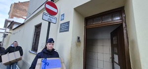 policjantka oraz inna osoba przenoszą zepraną odzież do budynku