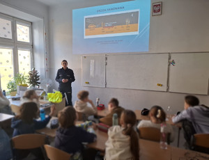 policjantka prowadzi zajęcia dla grupy uczniów w sali lekcyjnej