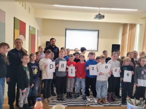 dzieci pozują do zdjęcia z policjantami prowadzącymi zajęcia o bezpieczeństwie