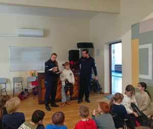 dziecko otrzymuje od policjantów nagrodę konkursową