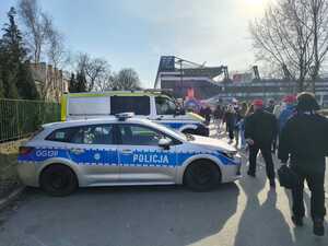 oznakowane radiowozy zaparkowane nieopodal stadionu przy ul. Reymonta. Obok widać kibiców zmierzających na mecz