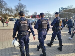Trzech umundurowanych policjantów patrolujących pieszo rejon przy stadionie