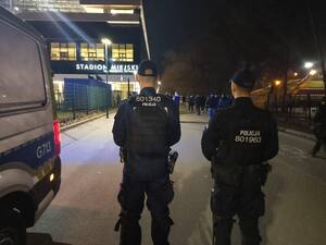 dwóch umundurowanych policjantów stojących przy radiowozie w rejonie stadionu przy ul. Reymonta