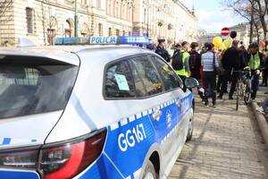 oznakowany radiowóz zaparkowany w rejonie ulicy Basztowej, przed którym widać osoby biorące udział w marszu
