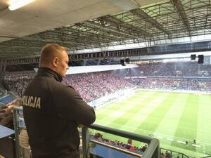 umundurowany policjant obserwujący zachowanie kibiców na stadionie
