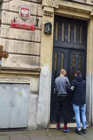 nieumundurowany policjant prowadzi zatrzymanego do budynku komisariatu