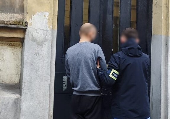 nieumundurowany policjant prowadzi zatrzymanego do budynku komisariatu