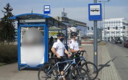 policjanci w patrolu rowerowym stojący przy przystanku komunikacji miejskiej
