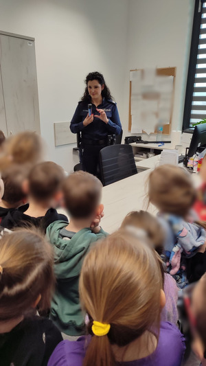 Policjantka pokazuje dzieciom policyjne wyposażenie