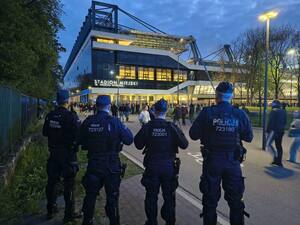 czterech umundurowanych policjantów stojących przed stadionem
