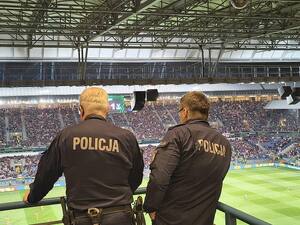 policjanci dowodzący zabezpieczeniem meczu obserwują kibiców zgromadzonych na stadionie