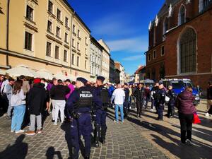 umundurowani policjanci obserwujący zachowanie kibiców zgromadzonych w centrum miasta