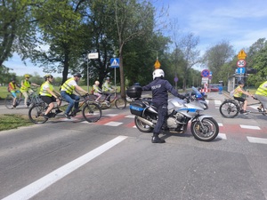 policjant dba o bezpieczeństwo grupy jadącej na rowerach podczas pokonywania przejazdu dla rowerów