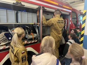 strażak pokazuje uczniom wyposażenie wozu strażackiego
