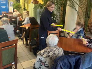 policjantka rozdaje seniorom opaski odblaskowe