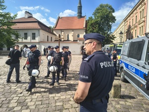 umundurowani policjanci stojący przed radiowozami