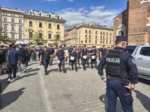 umundurowani policjanci na Rynku Głównym idą przed grupą osób biorącą udział w marszu