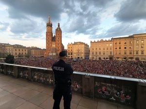 umundurowany policjanti na Rynku Głównym idą przed grupą osób biorącą udział w marszu