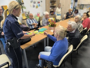 policjantka rozdaje elementy odblaskowe uczestnikom spotkania