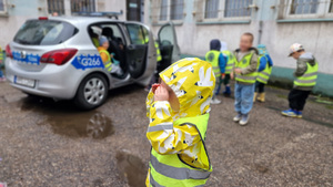 dzieci przy radiowozie obok budynku komisariatu