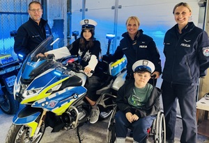 wspólne zdjęcie chłopca, jego przyjaciółki i policjantów przy służbowym motocyklu