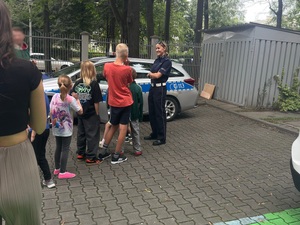 uczestnicy spotkania z policjantami stoją przy radiowozie