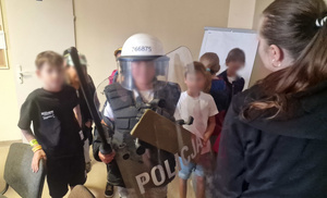 koloniści przymierzają elementy policyjnego wyposażenia