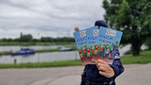 policjantka trzyma w ręku i prezentuje ulotki edukacyjne