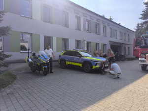 uczestnicy pikniku i policjant przy pojazdach służbowych