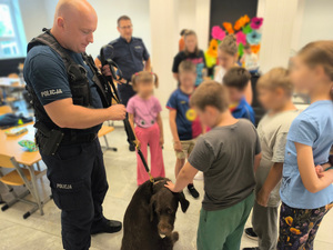 policyjny przewodnik z psem służbowym w otoczeniu dzieci