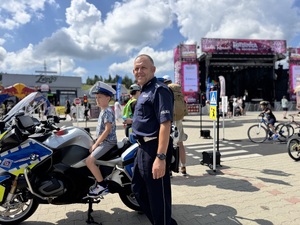 policjant ruchu drogowego przy służbowym motocyklu na którym siedzi dziecko