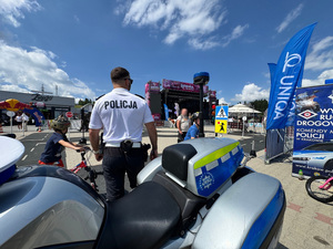 policjant ruchu drogowego przy służbowym motocyklu obok dziecko jadące jednośladem